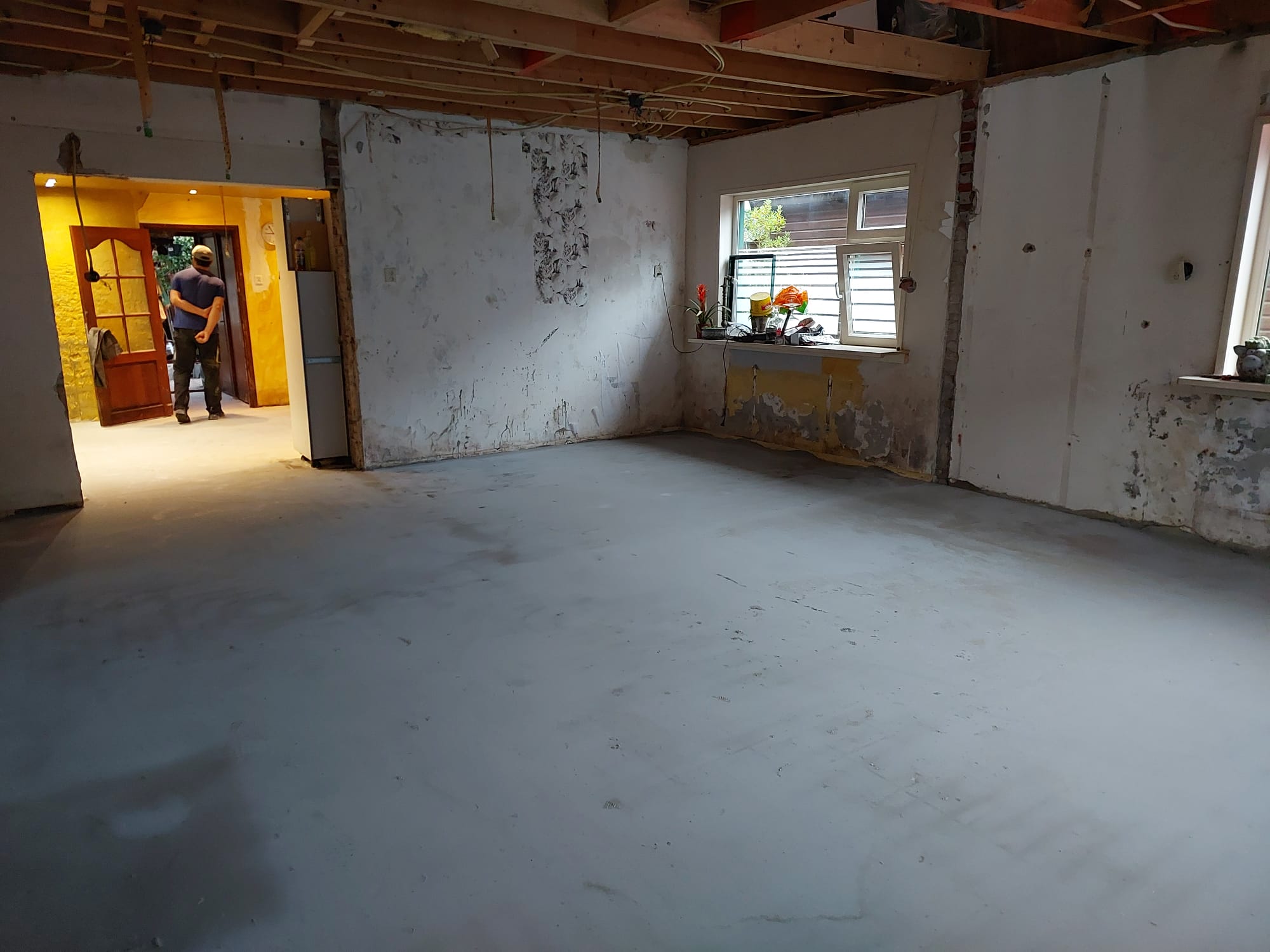 Woonkamer met oude balkenplafond en blote muren voorafgaand aan de renovatie