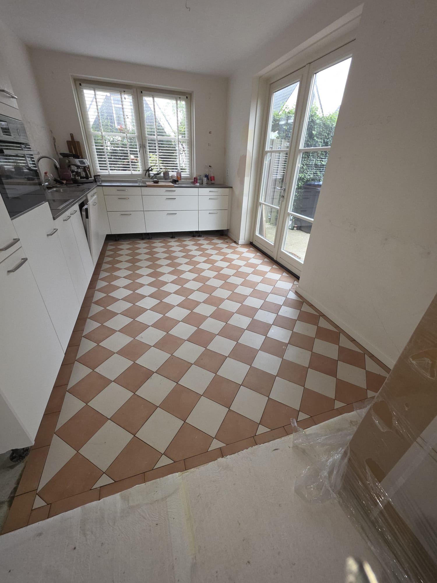 Overzicht van de keuken met schaakbordvloer in gebroken wit en terracotta