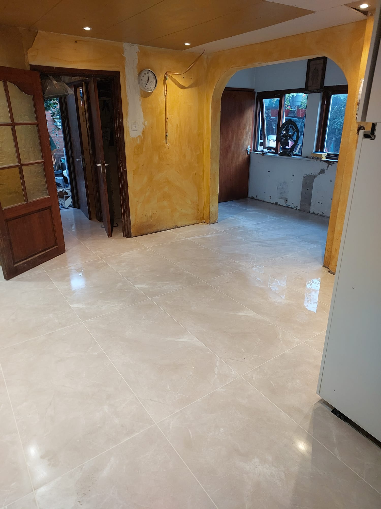 Woonkamer met nieuwe tegelvloer, doorkijk naar de keuken