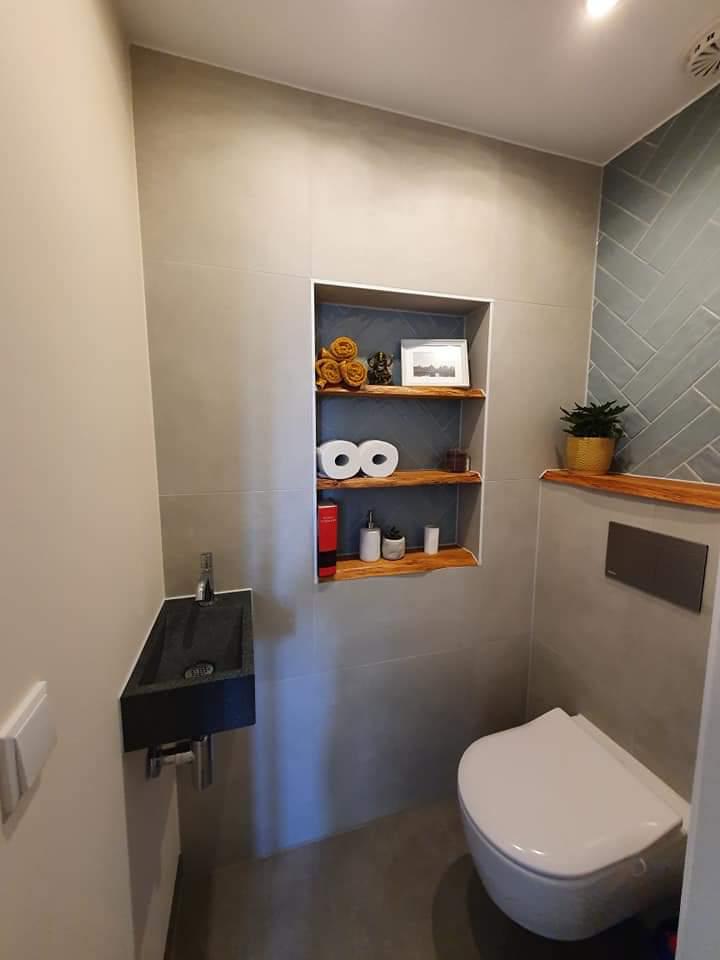 Overzicht van de toilet met blauwgrijze visgraattegel en houten plank
