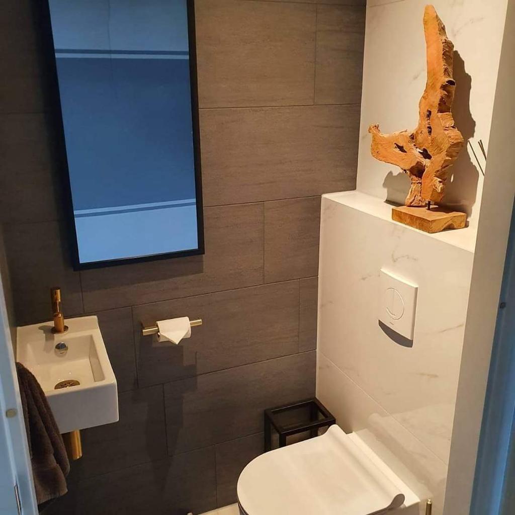 Tweede toilet in donkere tinten met marmeren steunbalk, spiegel en gouden kraan