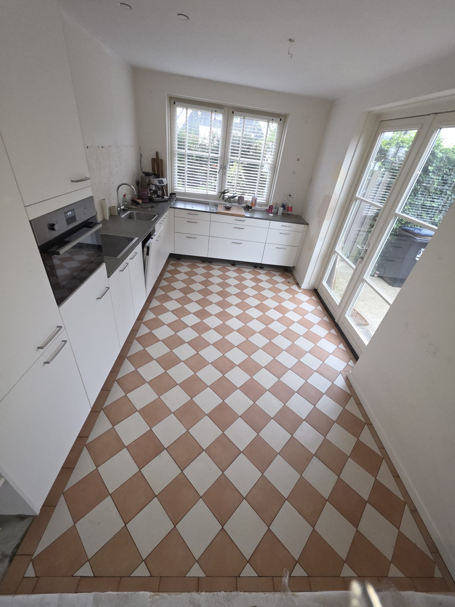 Keuken met nieuw gerenoveerde vloer in gebroken wit en terracotta schaakbordpatroon