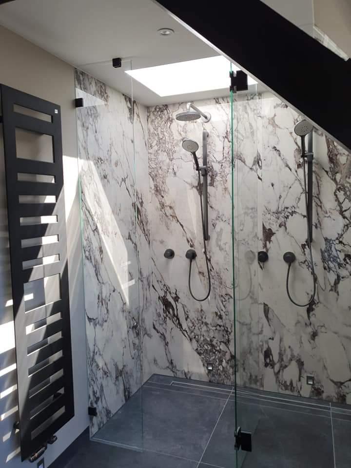 Walk-in douche met marmer-look wandtegels en dubbele regendouche onder het dakraam